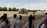 Children watch farmer sowing seed on the field